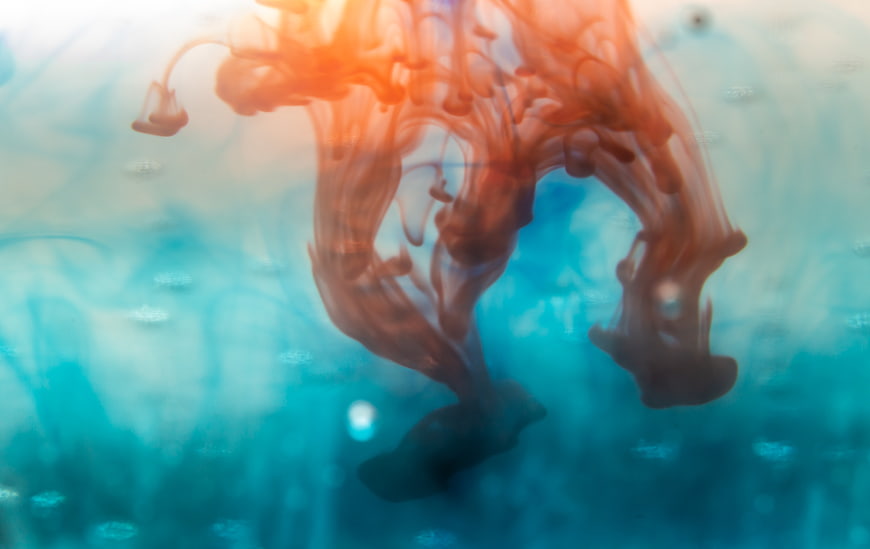 Abstract Orange Ink Swirling in Blue Water