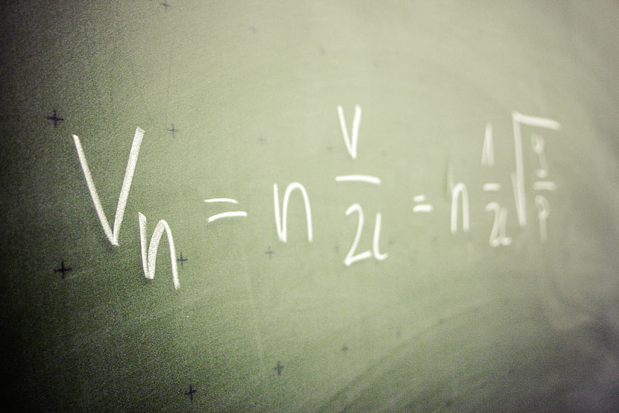 Physics formula written in chalk on a green blackboard