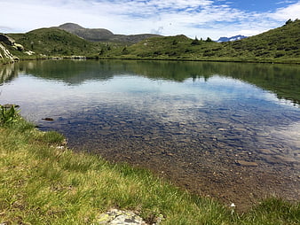 Crystal Clear Alpine Lake with Rocky Bottom and Green Hills