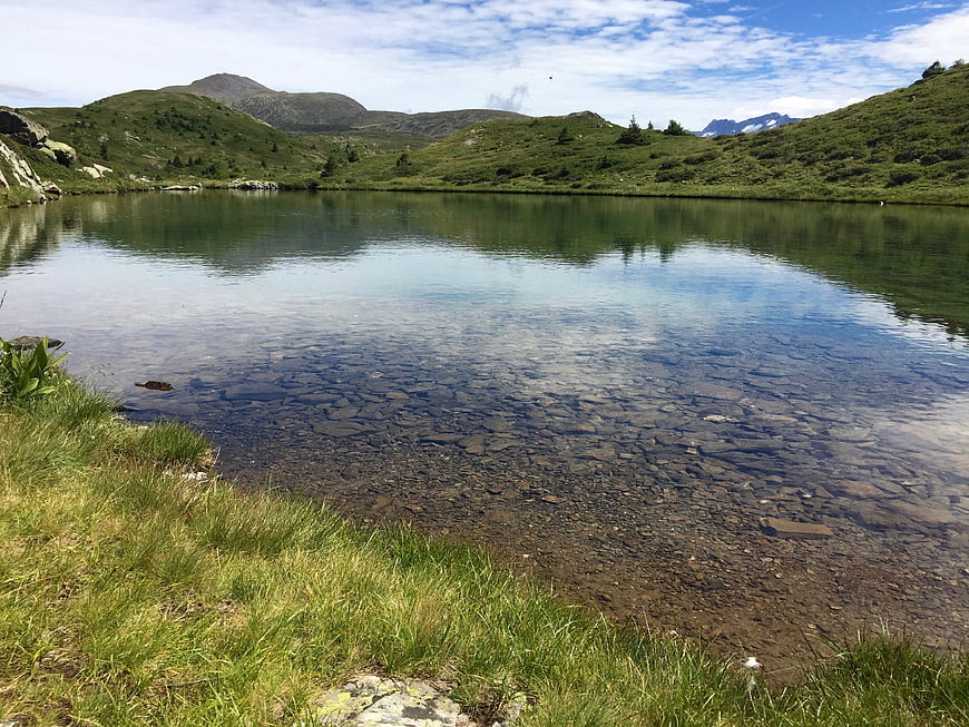 Crystal Clear Alpine Lake with Rocky Bottom and Green Hills