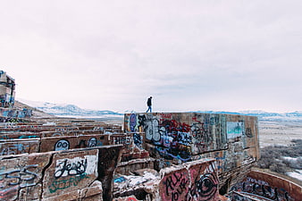 Lone figure walking on graffiti-covered concrete ruins