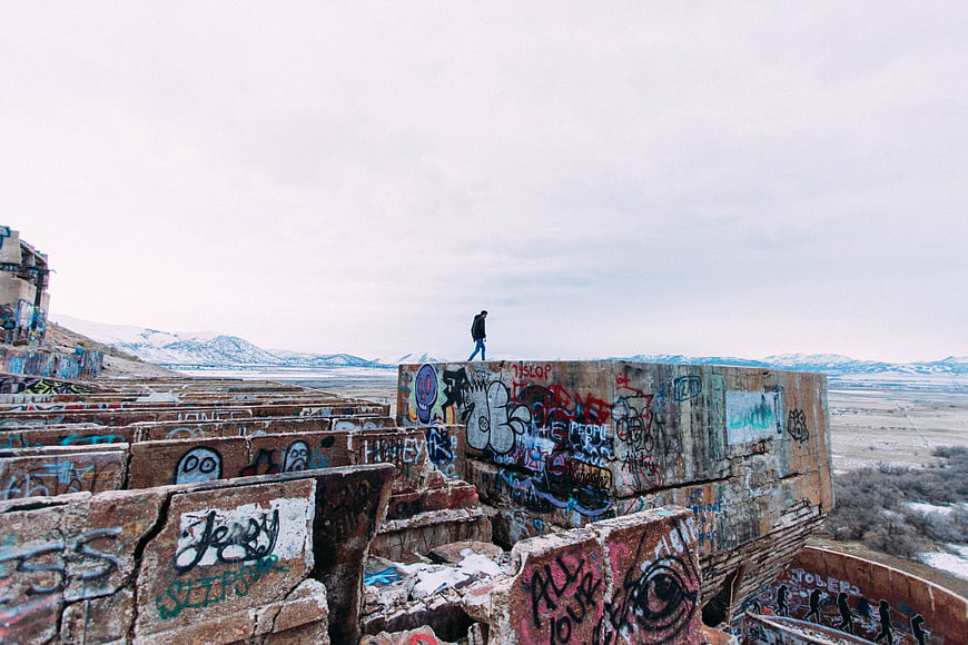 Lone figure walking on graffiti-covered concrete ruins