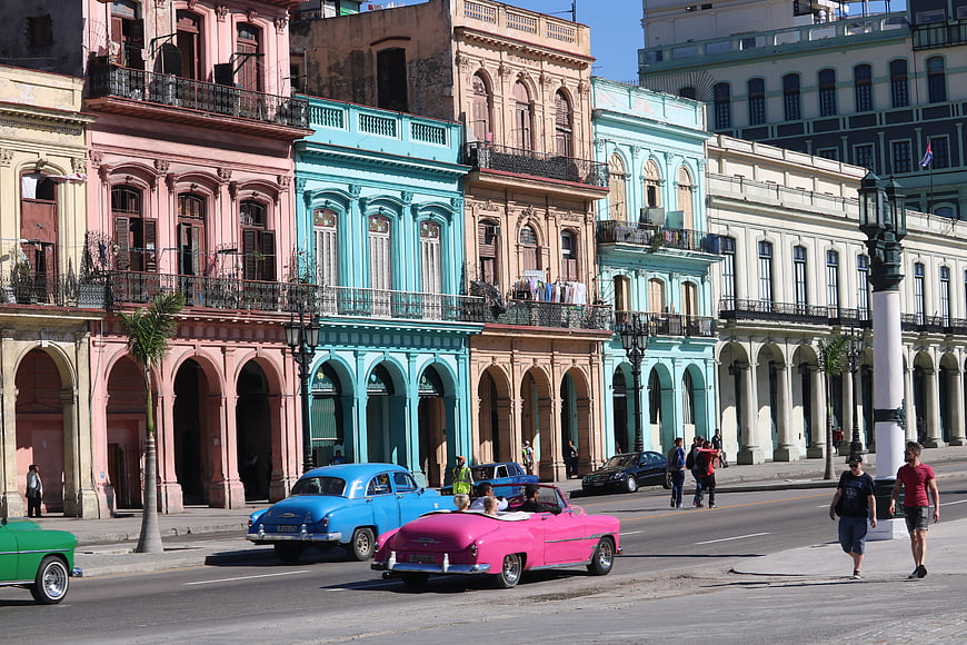 Vintage cars driving past colorful colonial buildings in Havana