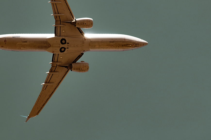 Commercial Airplane Flying Overhead Against Blue Sky