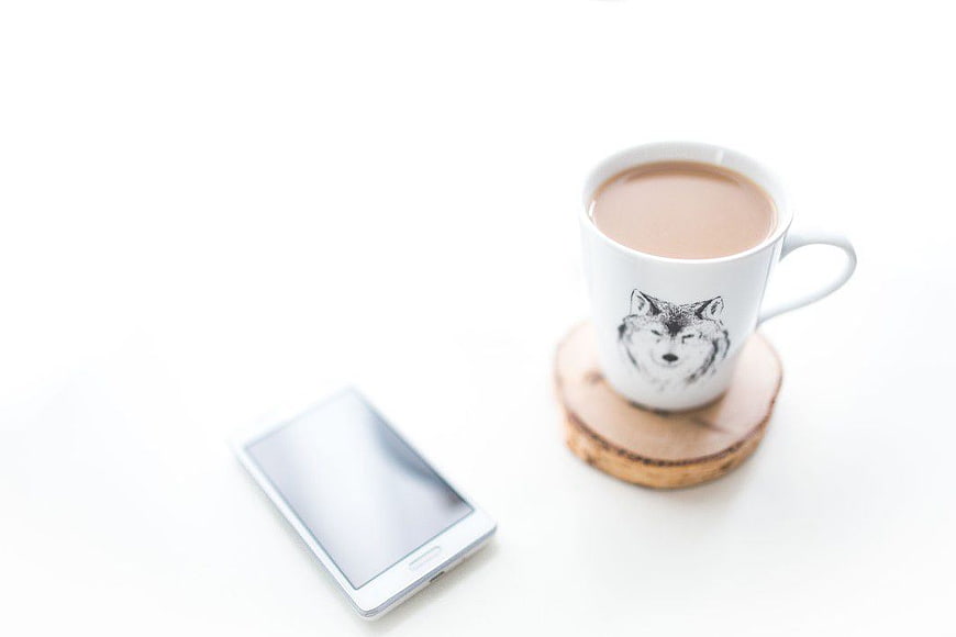 White Smartphone and Coffee Cup on Wooden Coaster