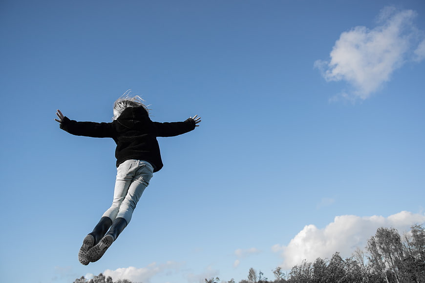 Child jumping in the air against blue sky