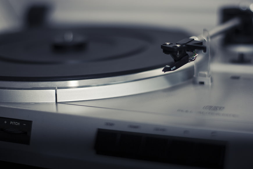 Close-up of silver turntable tonearm and vinyl record