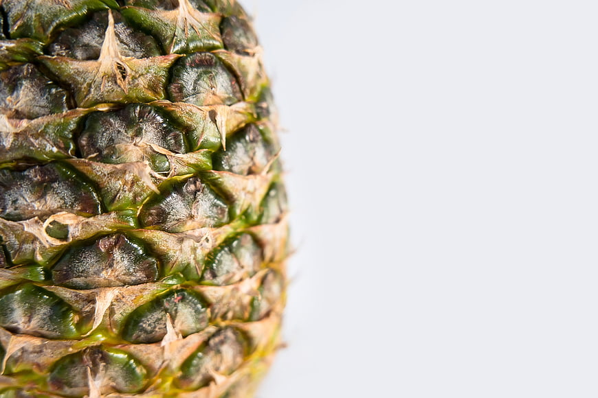 Close-up of textured pineapple skin on white background