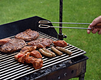 Assorted meats and sausages grilling on a charcoal barbecue outdoors