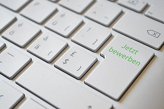 Close-up of white keyboard with green 'Jetzt bewerben' text on key