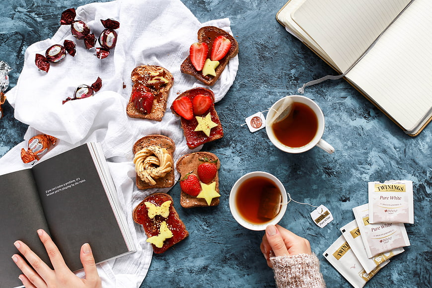 Flat lay of toast, tea, and books on blue background