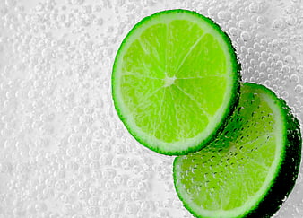 Fresh Lime Slices on White Surface with Water Droplets