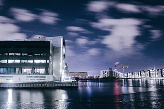 Modern waterfront architecture at night with long exposure clouds