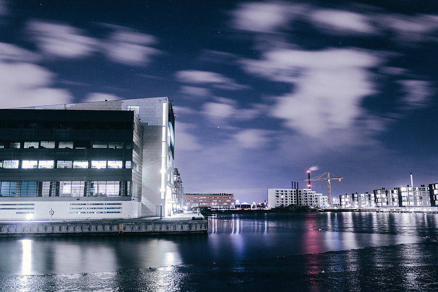 Modern waterfront architecture at night with long exposure clouds