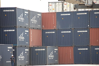 Stacked Shipping Containers at Port with Worker