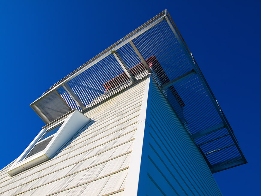 Low angle view of white lighthouse tower against blue sky
