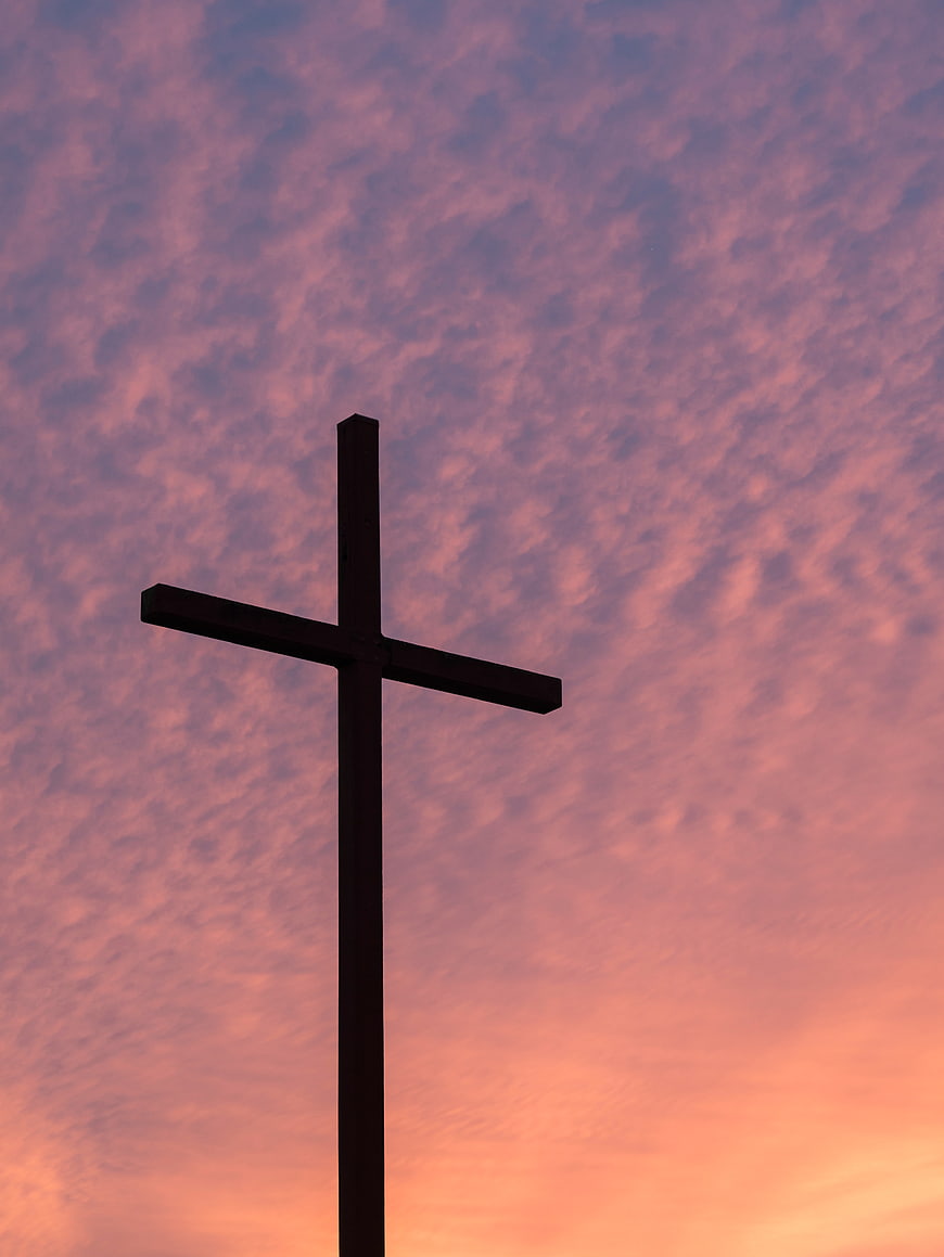 Silhouette of a Cross Against a Pink and Purple Sunset Sky