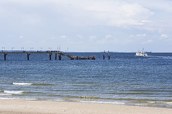 Sandy beach with pier and ferry on the Baltic Sea