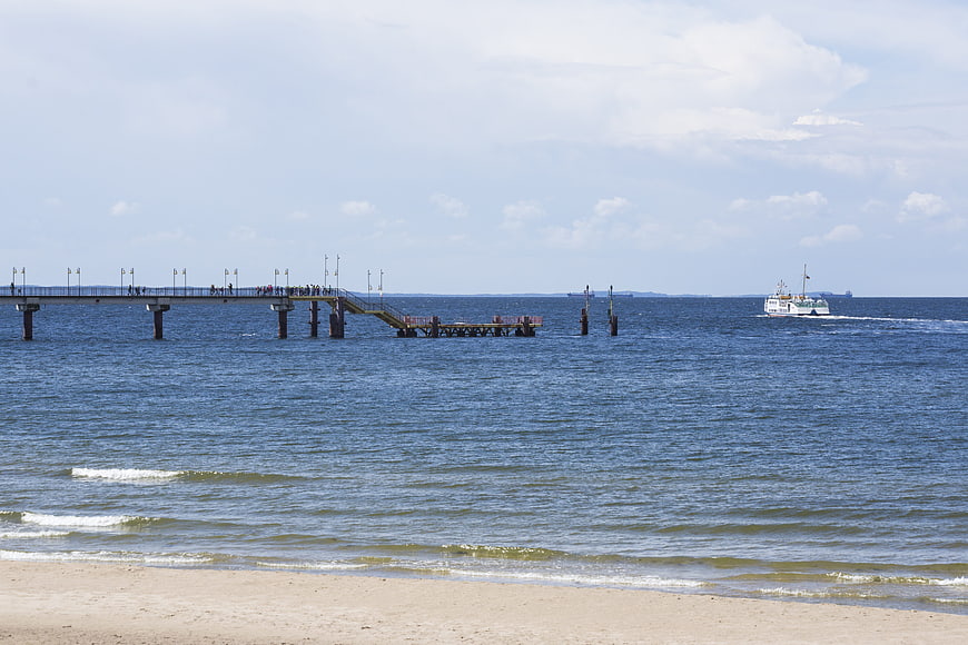 Sandy beach with pier and ferry on the Baltic Sea