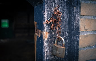 Rusty padlock and chain on weathered blue wooden door
