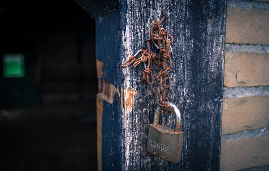 Rusty padlock and chain on weathered blue wooden door