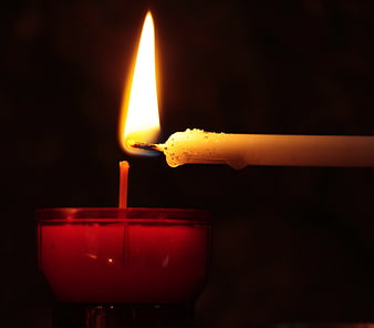 Lighting a red tea light candle with a taper candle