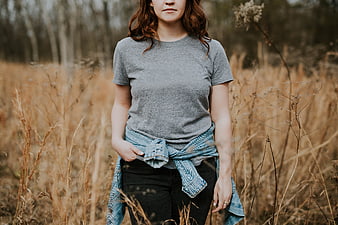 Woman in grey t-shirt and jeans standing in autumn field