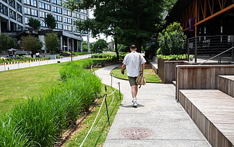 Man Walking on Path in Modern Urban Garden