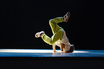 Young boy breakdancing on stage in green sweatpants