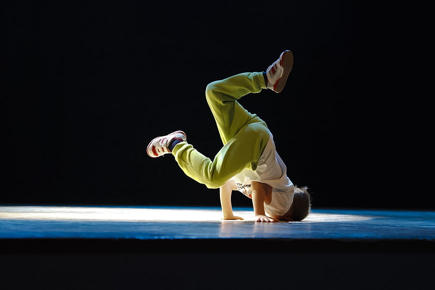 Young boy breakdancing on stage in green sweatpants