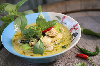 Thai Green Curry with Chicken and Basil on Rustic Wooden Table
