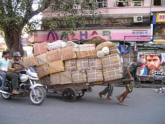 Indian laborers pulling heavily loaded cart on street