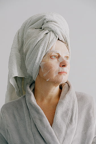 Woman with face mask and towel wrapped hair in bathrobe