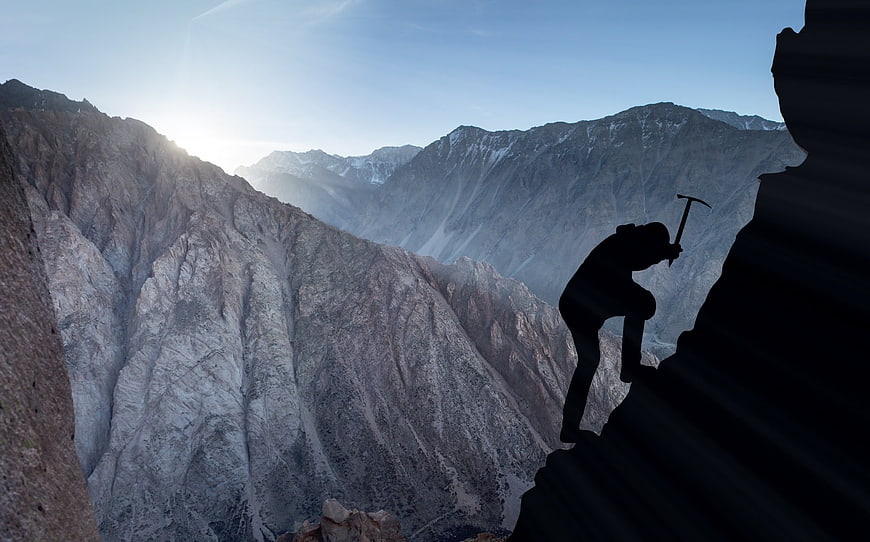 Silhouette of Rock Climber Scaling Mountain Peak at Sunrise