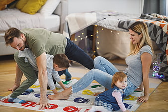 Happy Family Playing Twister Board Game on Living Room Floor