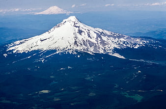 Aerial View of Snow-Capped Mountain Peak with Forested Slopes