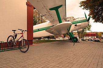 Vintage green and white airplane parked next to a bicycle