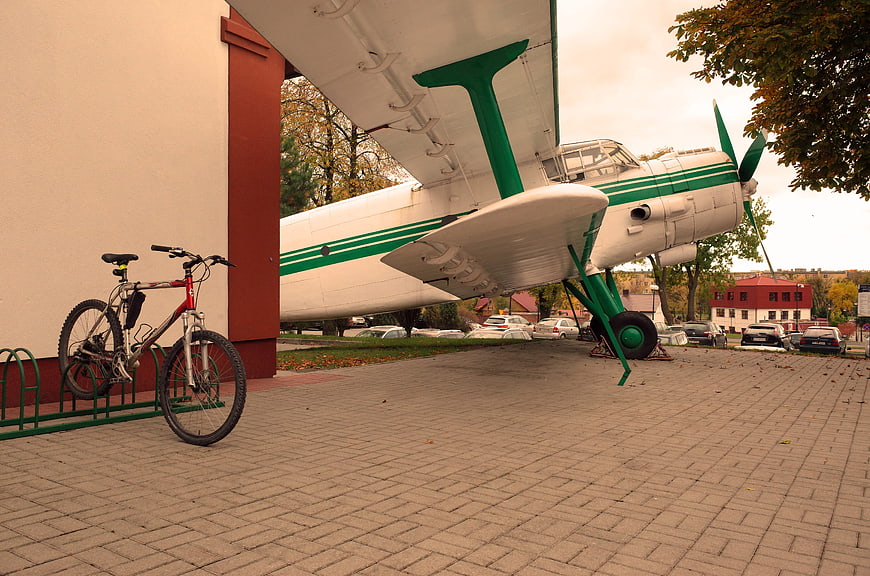 Vintage green and white airplane parked next to a bicycle