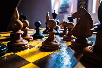 Close-up of wooden chess pieces on a yellow and black board