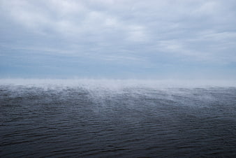 Misty ocean horizon with dark water and overcast sky