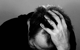 Black and white photo of man holding head in despair