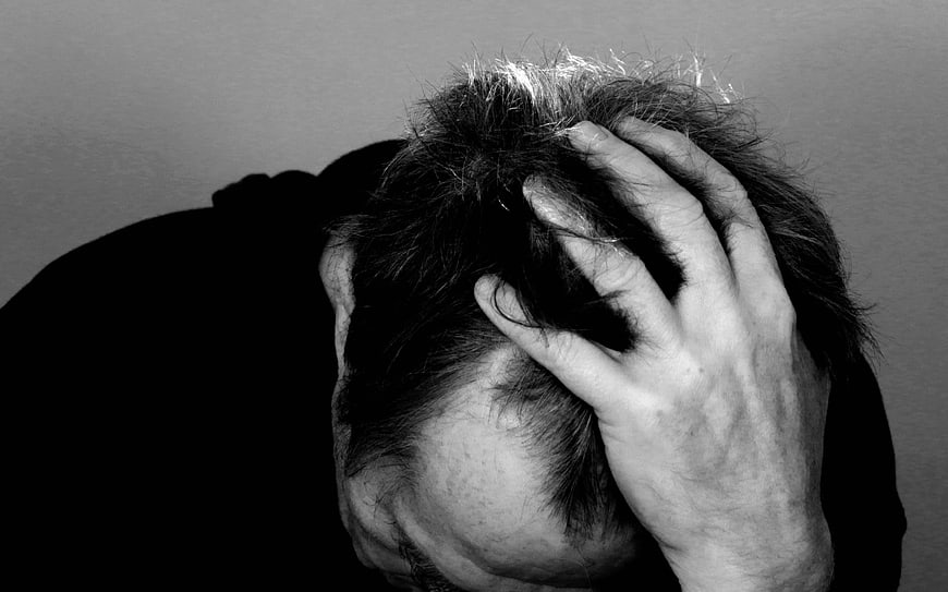 Black and white photo of man holding head in despair