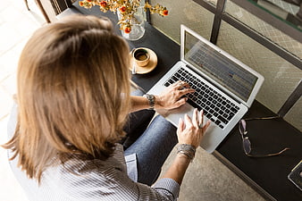 Overhead view of woman typing on laptop at cafe