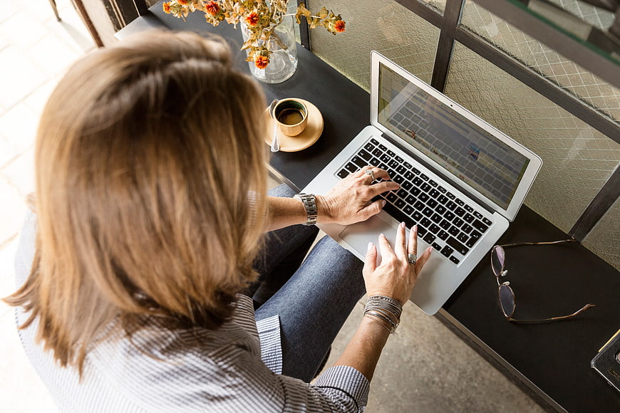Overhead view of woman typing on laptop at cafe