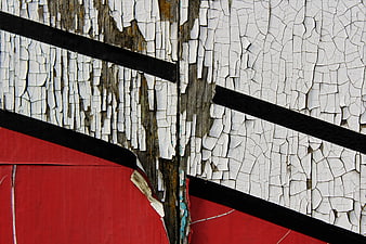 Abstract texture of peeling white and red paint on weathered wood