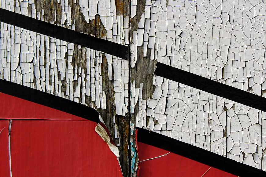 Abstract texture of peeling white and red paint on weathered wood