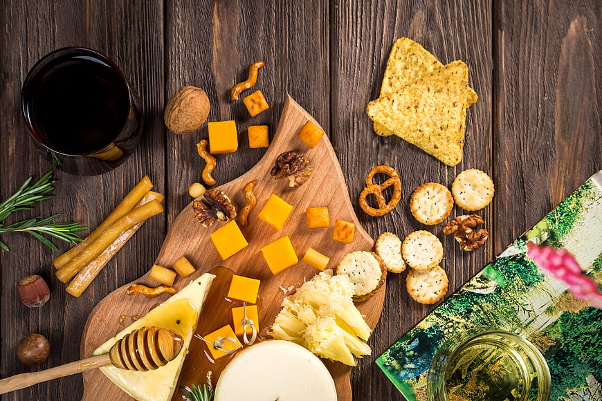 Overhead view of gourmet cheese board with wine and crackers