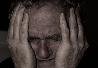 Close-up portrait of a distressed senior man holding his head in despair