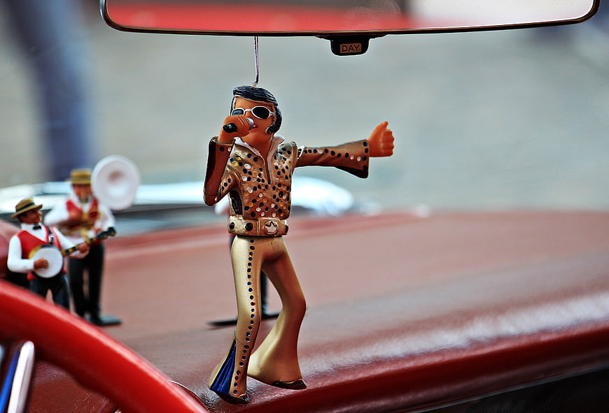 Elvis Presley Figurine Hanging From Rearview Mirror In Vintage Car