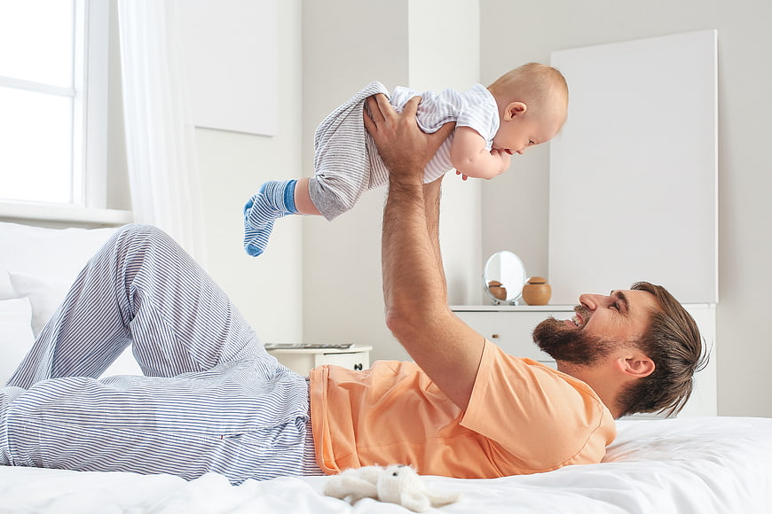 Happy Father Playing with Baby on Bed